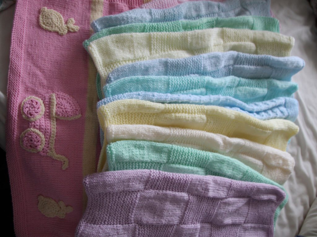 a selection of knitted baby blankets