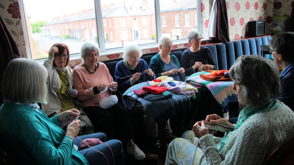 Helping hands group busily at work knitting